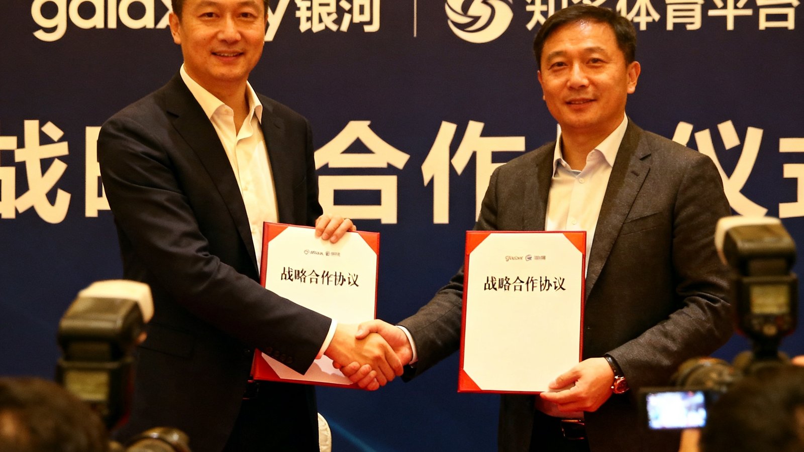 galaxy银河与知名体育平台战略合作签约仪式现场，双方代表握手并展示签署的协议文件